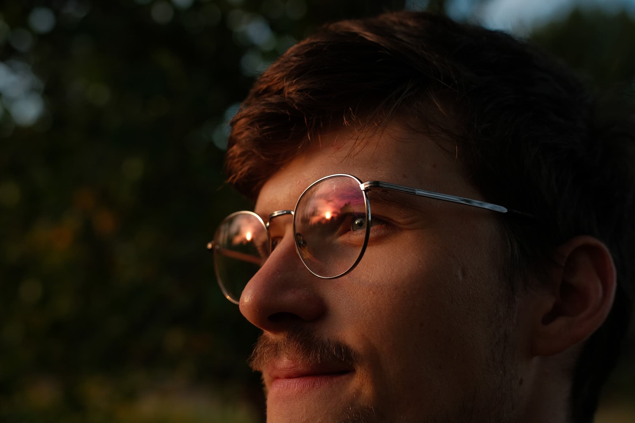 Portrait of Téo Prunier-Meline with the sunset reflected in his glasses